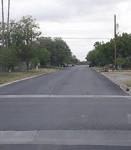A street with no cars on it and trees in the background.